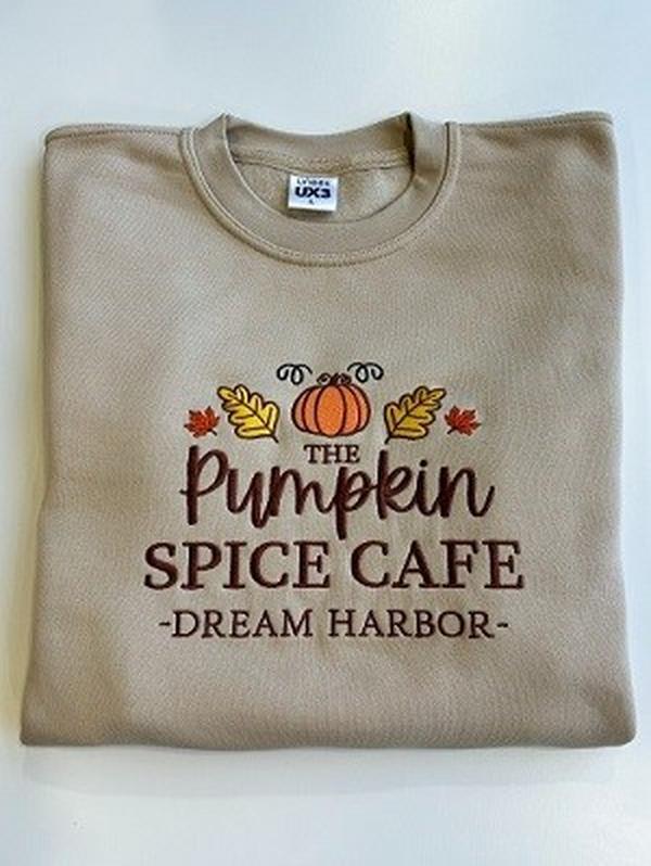 The Pumpkin Spice Café Official Embroidered Crew Neck Sweatshirt - A warm beige super-soft sweatshirt with embroidered details (a collegiate style centre slogan, a pumpkin & autumn leaves). Boxy fit, crew neckline, cuffed sleeves and bottom hem. 0